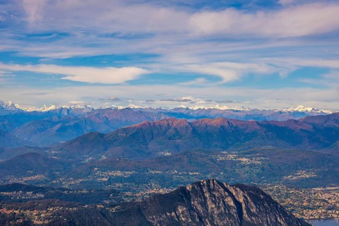 Aerial View over a Beautiful Mountainscape and And Snow Capped Mountain and with Floating Clouds in a Sunny Day in Lugano