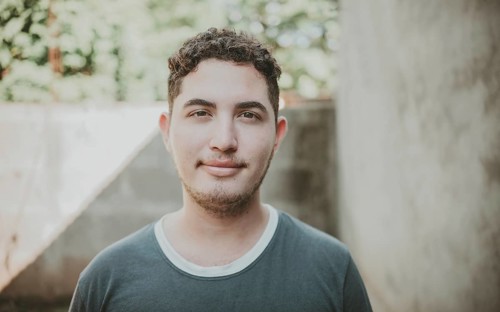 Portrait of cheerful young latin guy smiling at camera outdoors. Portrait of Latin American man looking and smiling at the camera