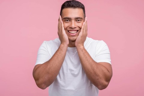 Front view smiley handsome man posing with palms his face