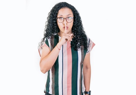 Young woman shushing you with her finger. Afro woman making silence gesture isolated