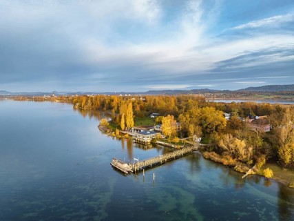 Aerial view of the Mettnau peninsula in western Lake Constance illuminated by the morning sun with the landing stage