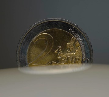 A 2-euro coin as a macro shot in the slot of a piggy bank