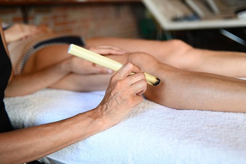 Therapist apply abdominal moxibustion chinese smoking stick moxa medicine burn mugwort in acupuncture point to caucasian adult fit woman to facilitate blood flow and general health through qi oriental...