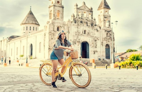 Lifestyle of a happy girl in hat on bicycle on the street. Granada