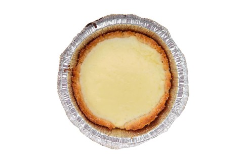 Top view of vanilla cake in a baking foil dish isolated on white background