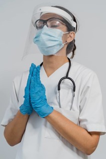 Female doctor with medical mask face shield praying