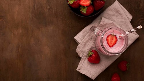Flat lay strawberry milkshake with straw copy space