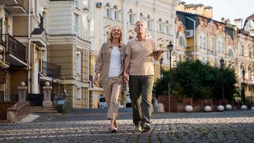 Front view elder couple out walk city with tablet