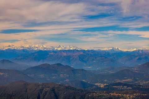 Aerial View over a Beautiful Mountainscape and And Snow Capped Mountain and with Floating Clouds in a Sunny Day in Lugano