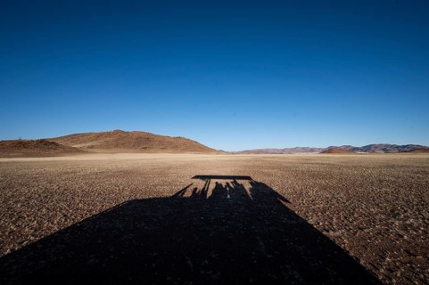 Shadow of safari vehicle in the Namib Desert with Tiras Mountains