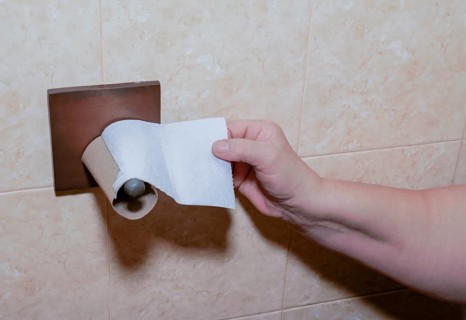 A woman's hand tries to reach for toilet paper but the roll has run out