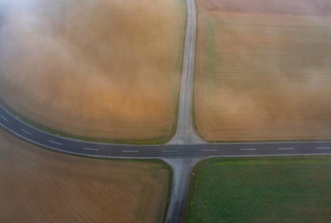 Drone view of a rural landscape shrouded in dense morning fog with a road junction near Prambachkirchen