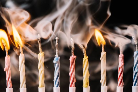 Burning extinguished candle against black background