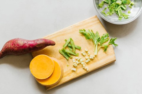 Elevated view sweet potato sliced pumpkin celery cutting board