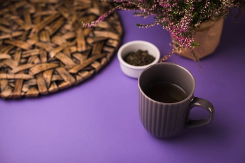 Black tea with herbs coaster purple background