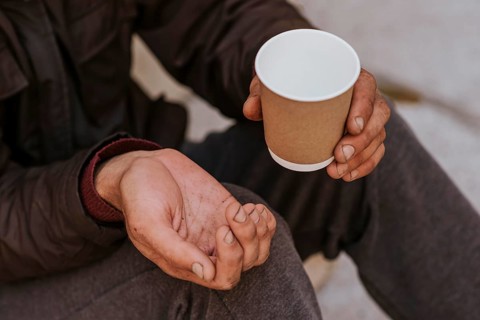 Homeless man holding hand out help empty cup