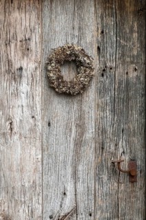 Very old weathered wooden door with a wreath of twigs and lichen