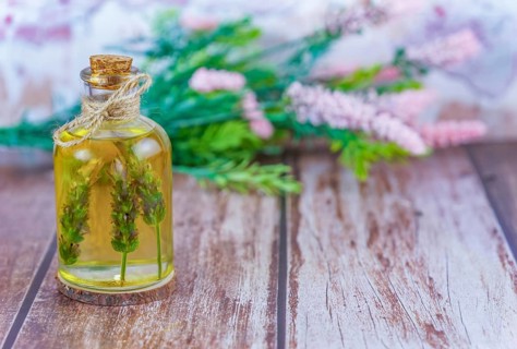Glass bottle with lavender oil with lavender branches inside on a wooden table