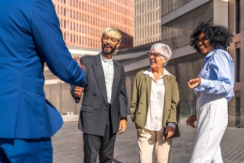 Multi-ethnic group of business people shaking hands when arrive to a meeting point outside a financial building