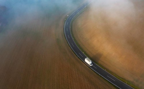 Drone view of a rural landscape shrouded in dense morning fog with a country road near Prambachkirchen