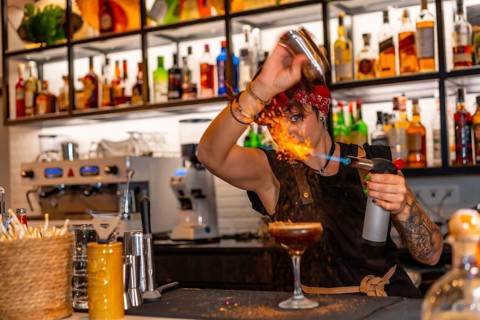 Bartender using torch to flaming the decoration of a cocktail