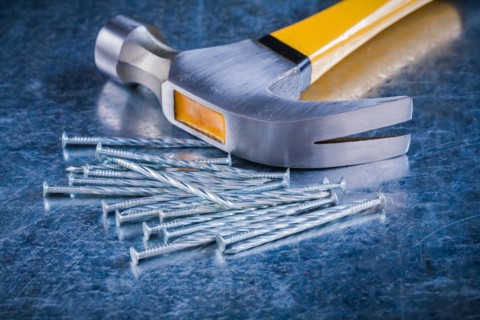 Long stainless steel nails with claw hammer on scratched metallic background Maintenance concept