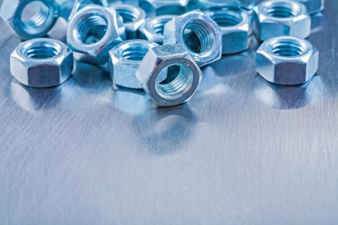 Large set of stainless steel nuts on metallic background Construction concept