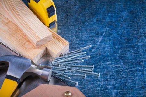 Composition of metal nails Hammer Wooden bricks Hacksaw Tape measure on scratched metal surface Construction concept