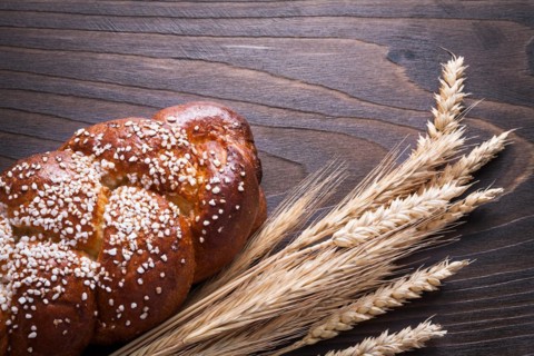 Long loaf of wheat rye ears on wooden background food and drink concept