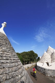 Cyclist between trulli near Noci