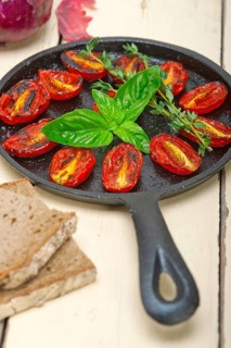 Oven baked cherry tomatoes with basil and thyme on a cast iron skillet