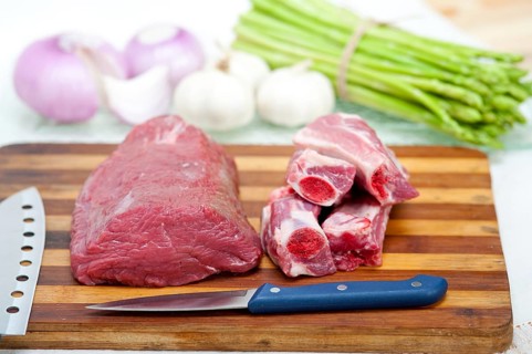 Raw beef and pork ribs with asparagus and herbs ready to cook