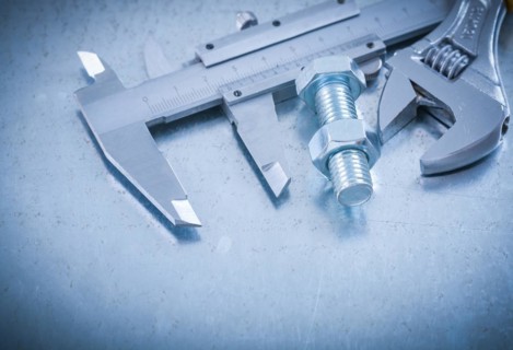 Metal brake caliper adjustable spanner bolt and nut on scratched metallic background construction concept
