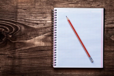 Pencil and clean square copybook on pine brown wooden board office concept