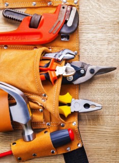 Tool belt with construction tools hammer screwdriver pliers spanner on wooden board