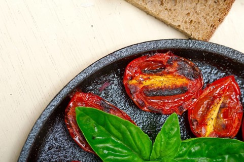 Oven baked cherry tomatoes with basil and thyme on a cast iron skillet