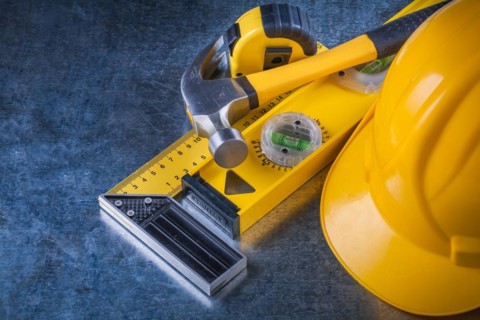 Measuring instruments Claw hammer and construction helmet on scratched metallic background Maintenance concept