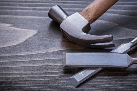 Claw hammer and flat chisel on vintage wooden panel Construction concept