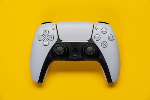 Controller of the PS5 Playstation game console from Sony in front of a monochrome yellow background