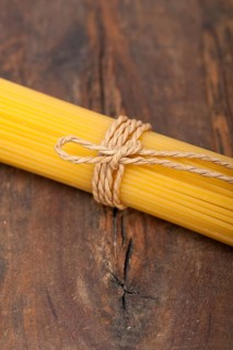 Italian pasta spaghetti tied with a rope on a rustic table