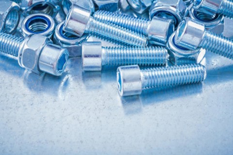 Composition of metal nuts and bolts on a flat metallic background Design concept