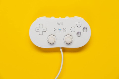 Classic game controller Nintendo Wii game console in front of plain yellow background