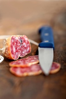 Slicing italian salame pressato pressed over old wood table