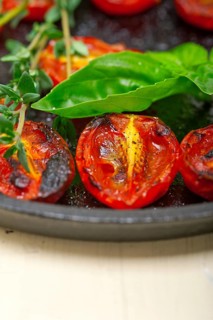 Oven baked cherry tomatoes with basil and thyme on a cast iron skillet
