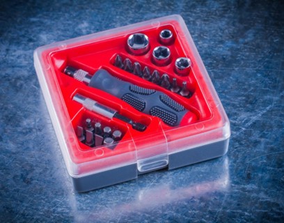 Closed toolbox with screwdriver and interchangeable bits on a metallic background Design concept