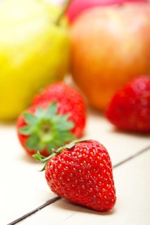 Fresh fruits apples pears and strawberry on a white wood table