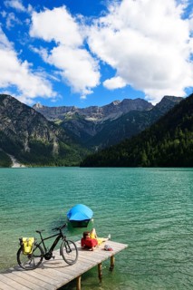 Cyclist taking a break on a wooden footbridge at Plansee
