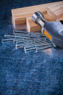 Metal nails claw hammer and wooden bolt on scratched metallic background copy space image construction concept
