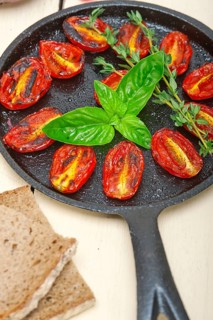 Oven baked cherry tomatoes with basil and thyme on a cast iron skillet