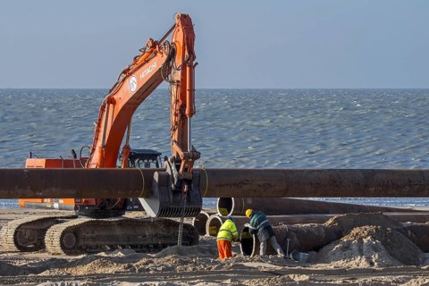 Dredging workers connecting pipes of pipeline during sand replenishment